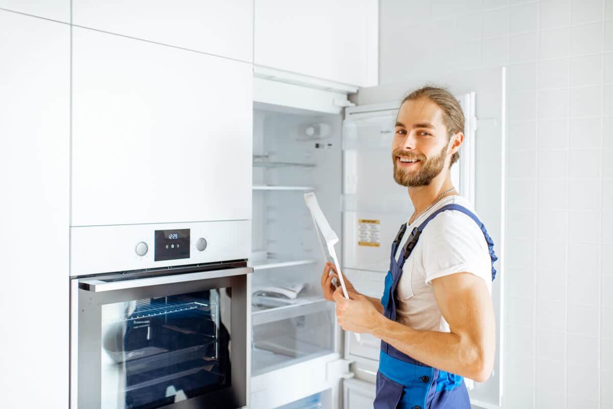 Arbeiter baut Kühlschrank in moderne Küche ein