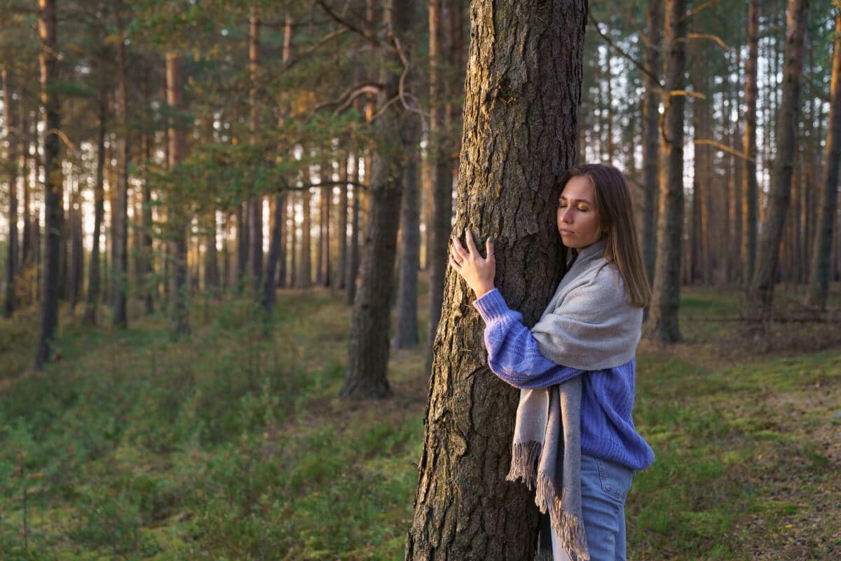 Frau umarmt Zirbenbaum im Wald