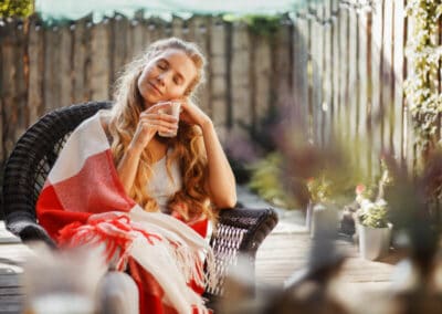 Junge Frau trinkt eingehüllt in einem roten Handtuch einen Tee